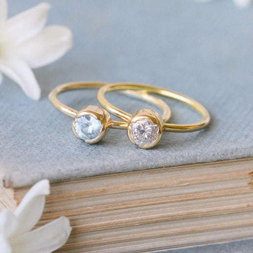 Two solitaire rings in gold sitting on a book