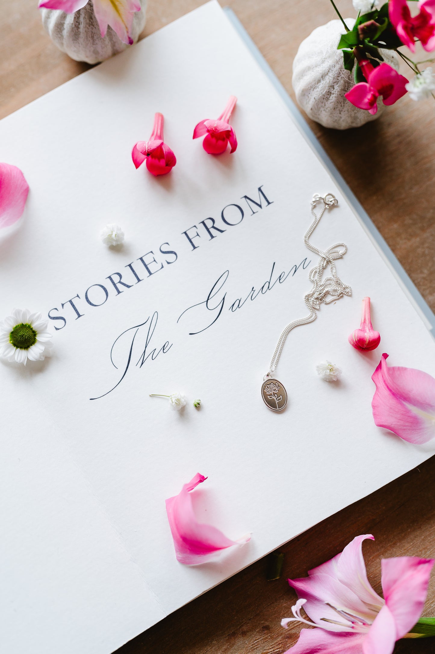 Chrysanthemum flower necklace lying on a book, with flowers in the background.
