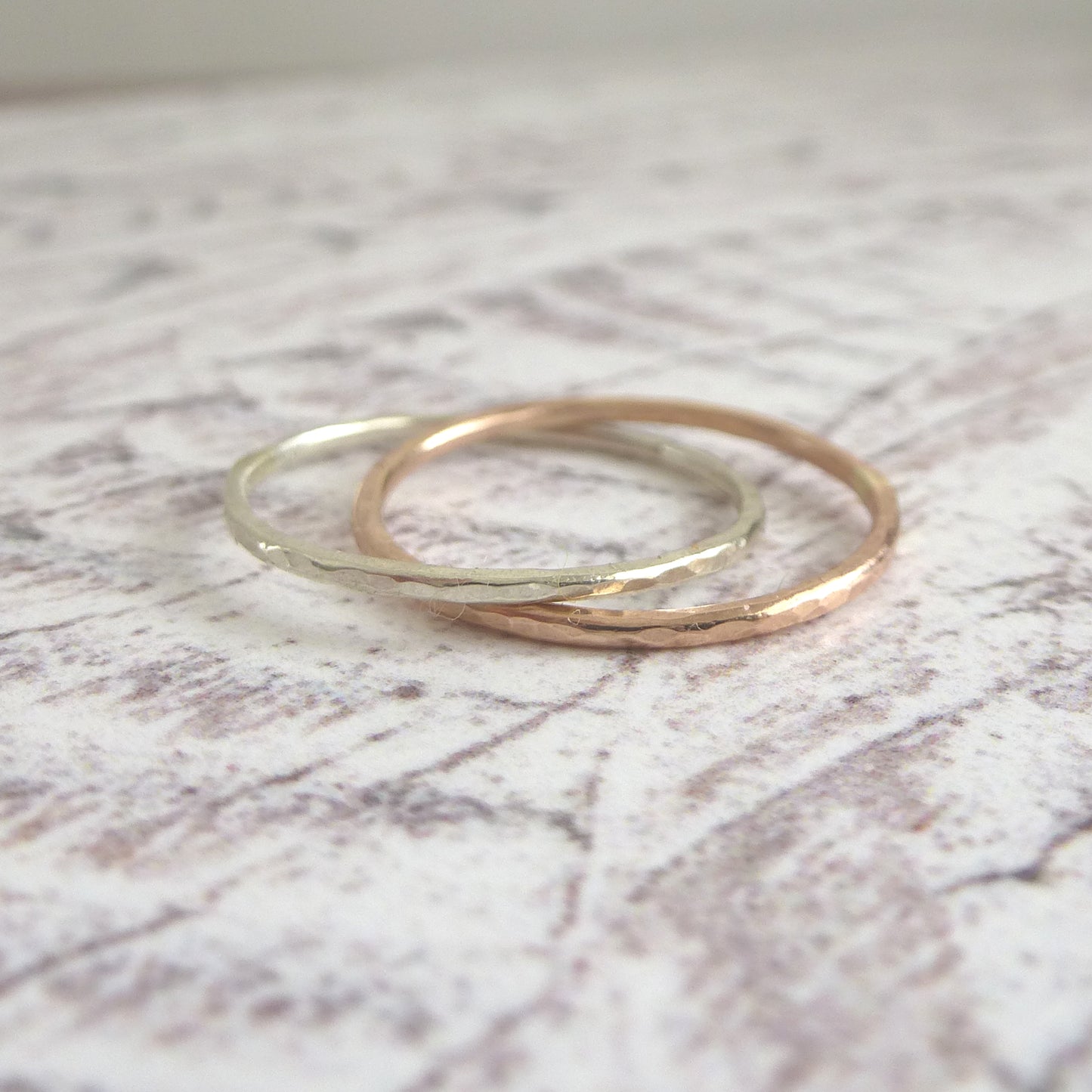 A pair of joined or russian wedding ring style bands in 9ct white and rose gold, with a hammered finish