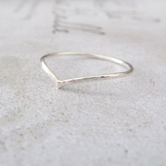 skinny wishbone ring in sterling silver, sitting on a marbled paper board