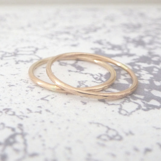 A pair of slim bands in recycled 9ct rose gold, one hammered one smooth