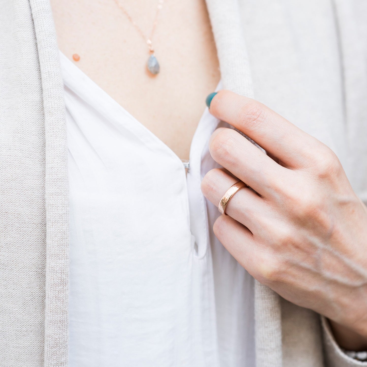 A 4mm 9ct rose gold wedding band, being worn over a white shirt and beige cardigan