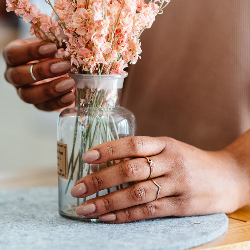 Wishbone wedding ring being worn, hand holding a vase of flowers