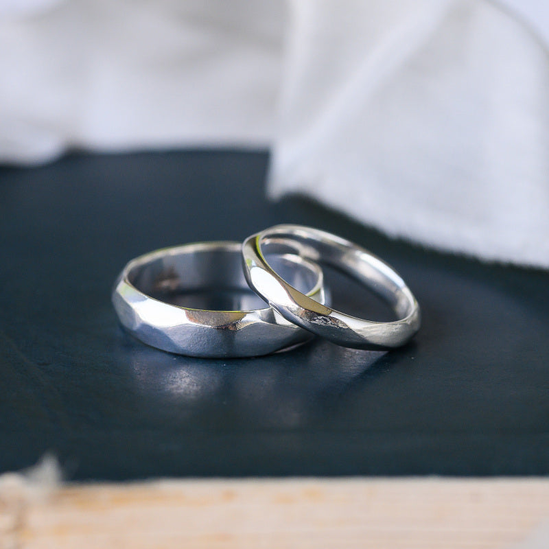Two carved silver wedding rings on a dark surface