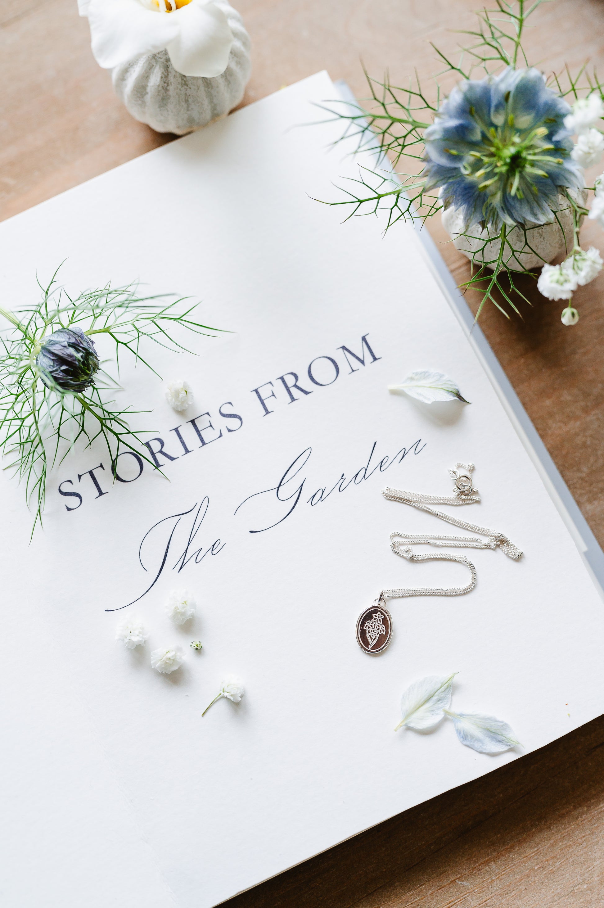 Narcissus necklace in sterling silver, on an open book with flowers.