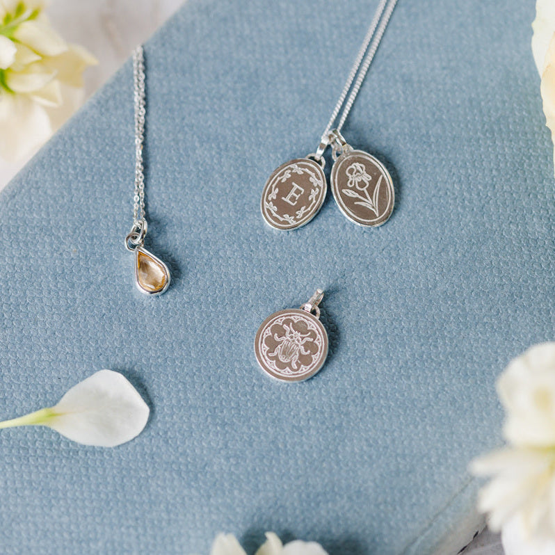 A selection of engraved necklaces, initial necklace shown in silver available made to order in gold