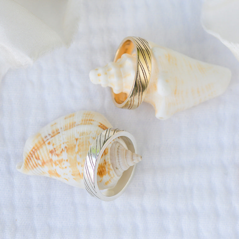 Sand Rings, two wedding rings with grooved details sitting on seashells.