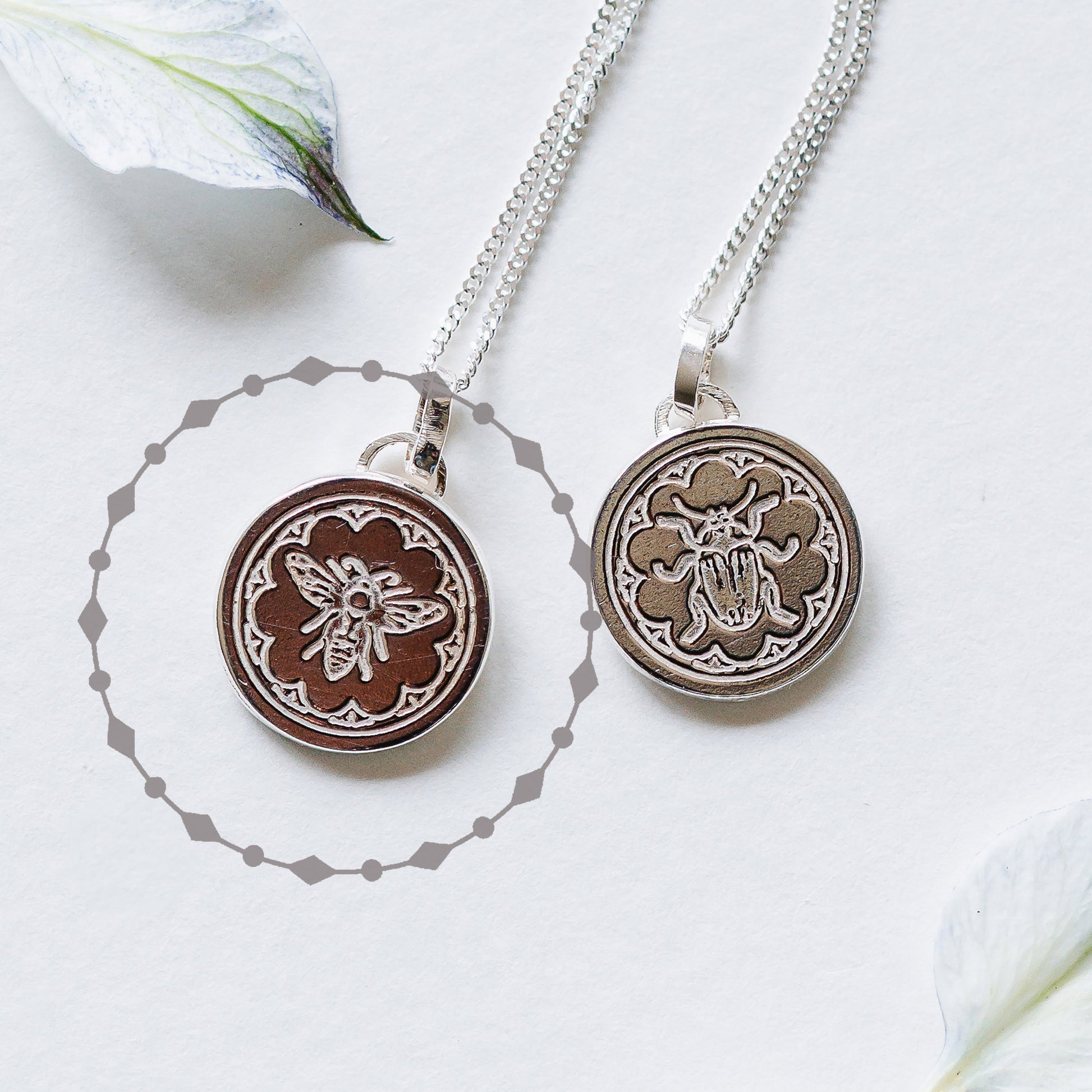 Two sterling silver necklaces with a delicate border, one with a bee and one a beetle. 