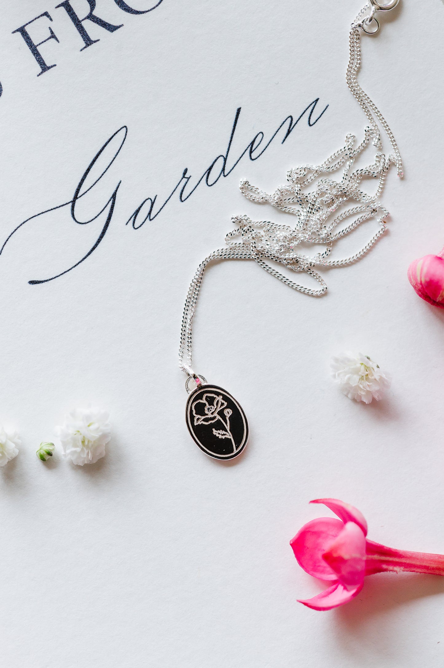 Sterling silver poppy necklace lying on a white background