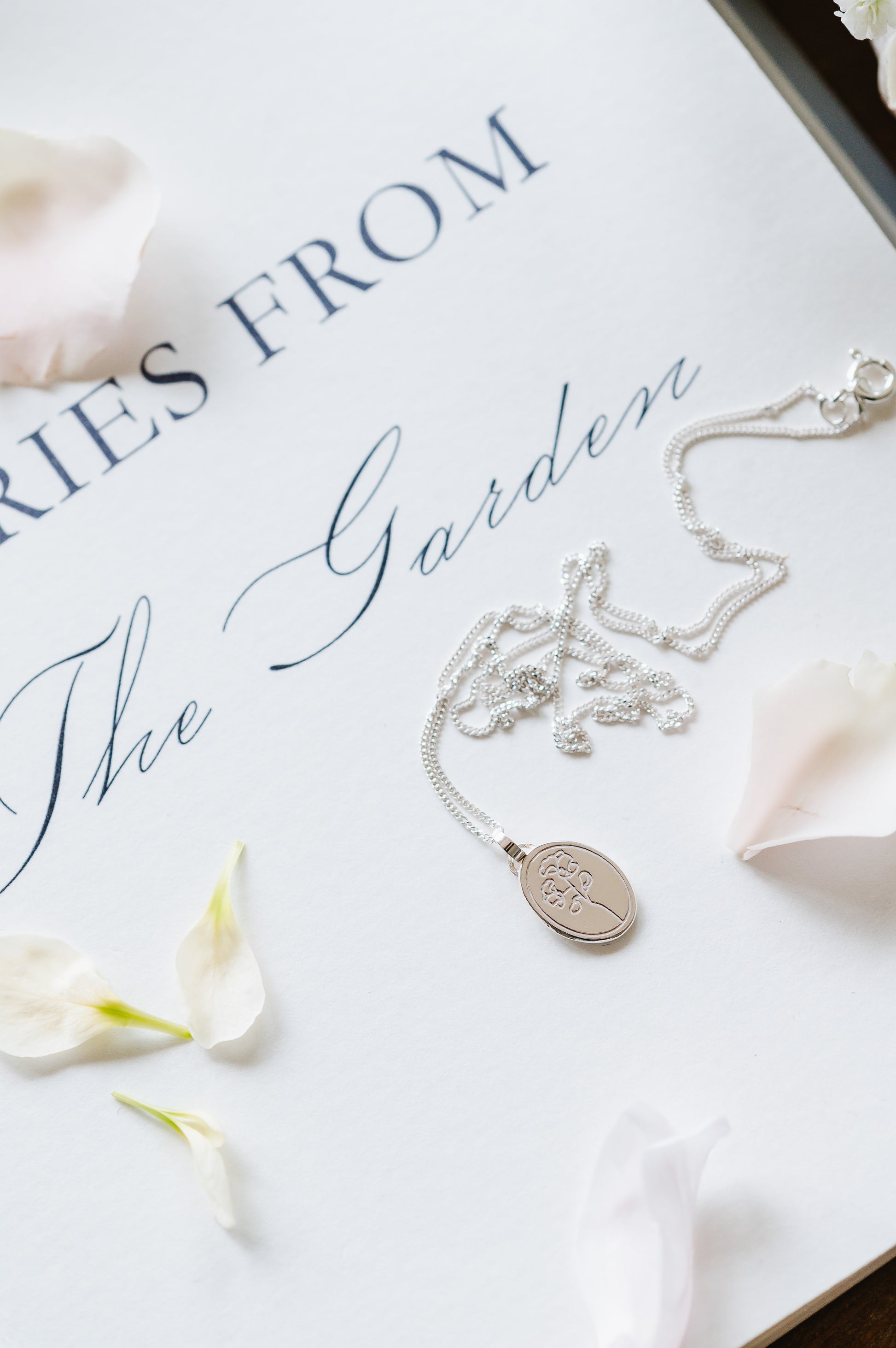 A stering silver necklace with a sweet pea flower. Oval coin necklace with a dainty sweet pea flower image. 