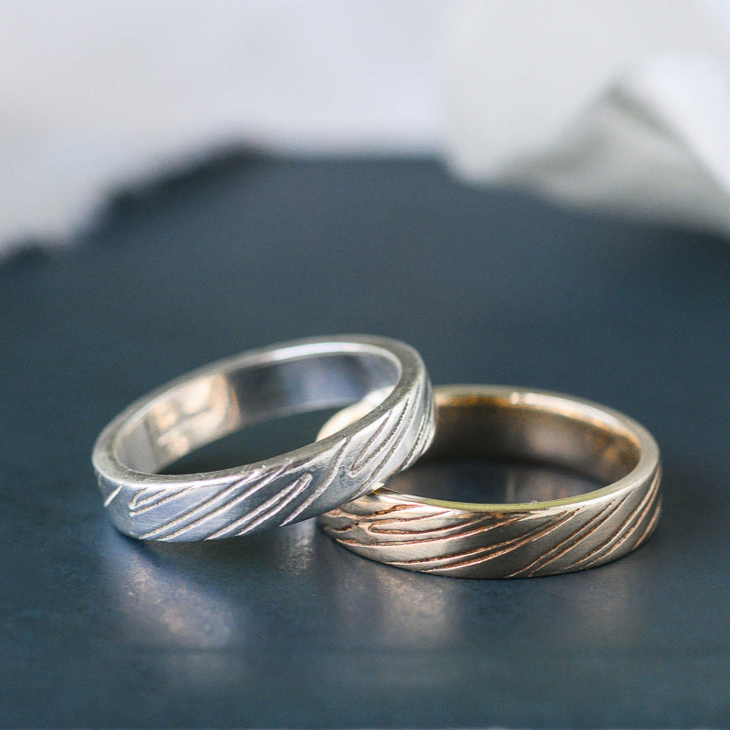 Sand rings two wedding rings with carved detail on a dark background