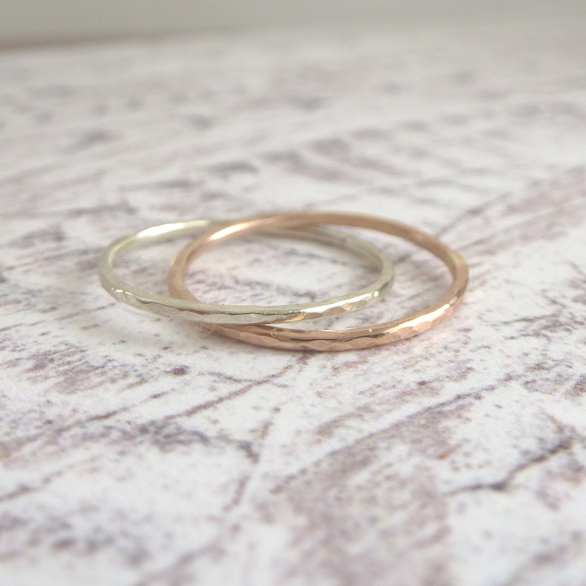 A pair of joined or russian wedding ring style bands in 9ct white and rose gold, with a hammered finish, close up