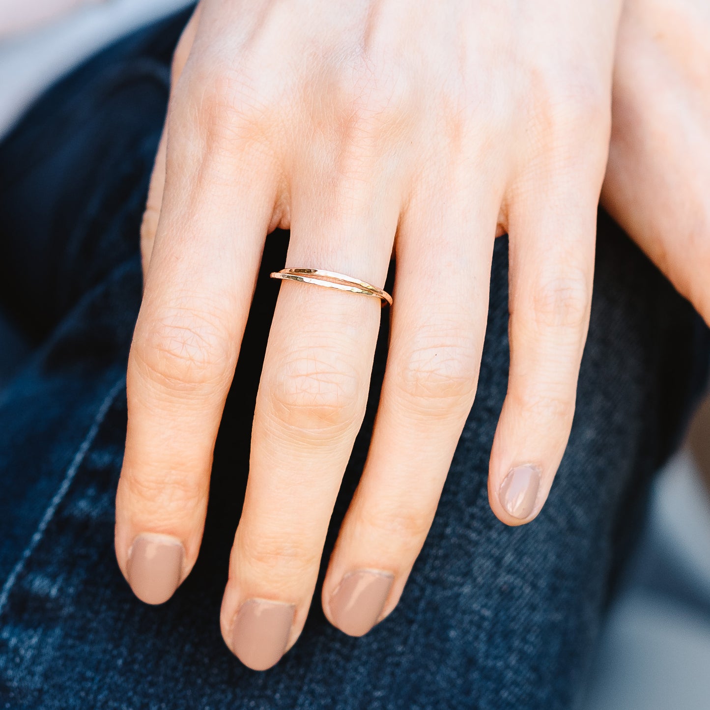 A pair of joined or russian wedding ring style bands in 9ct white and rose gold, with a hammered finish, being worn