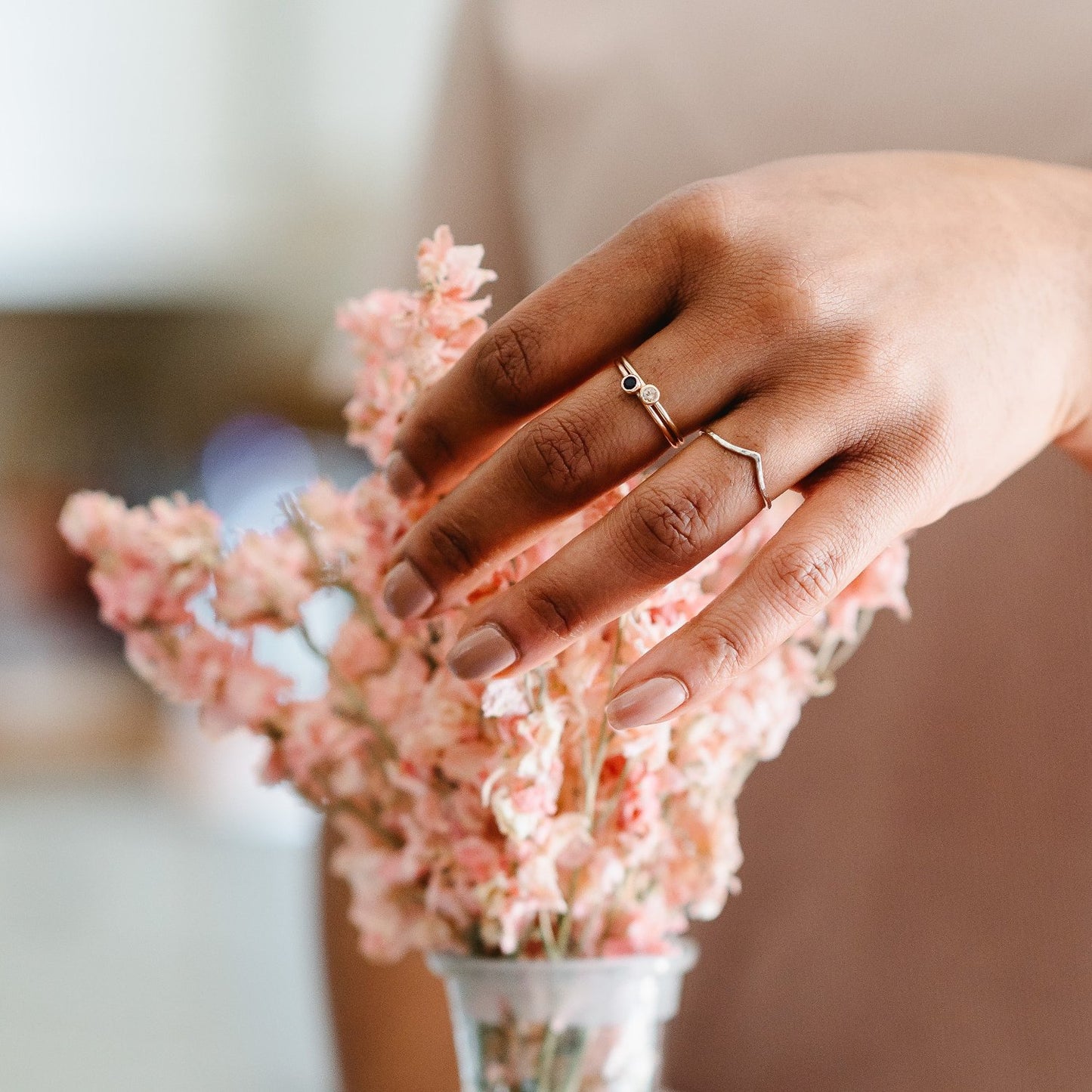 Slim 9ct white gold wishbone wedding ring. A simple wishbone ring being worn, with a couple of stone set rings on a hand arranging some flowers.