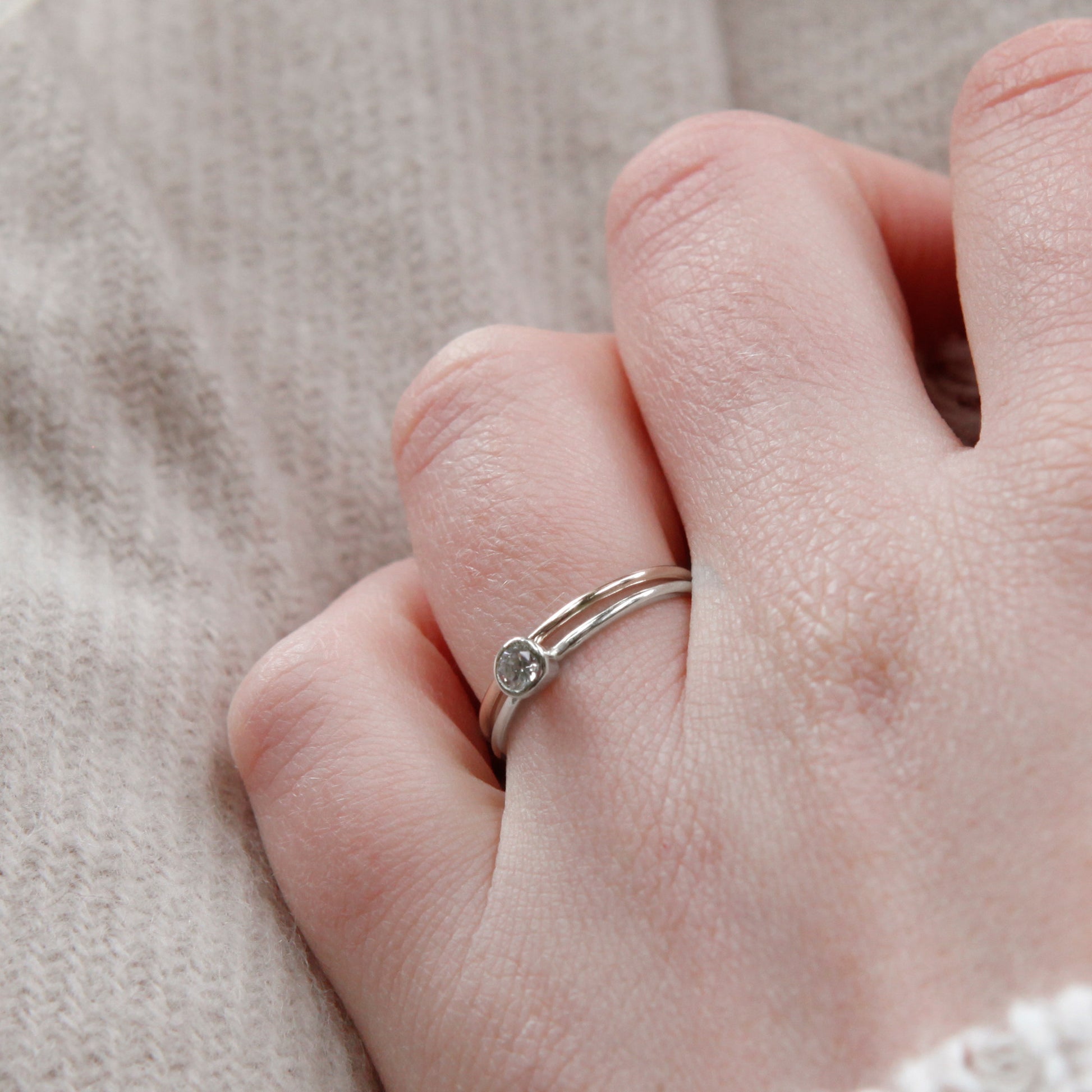 A close up of a pair of rings, one stone set one plain, 1.2mm bands