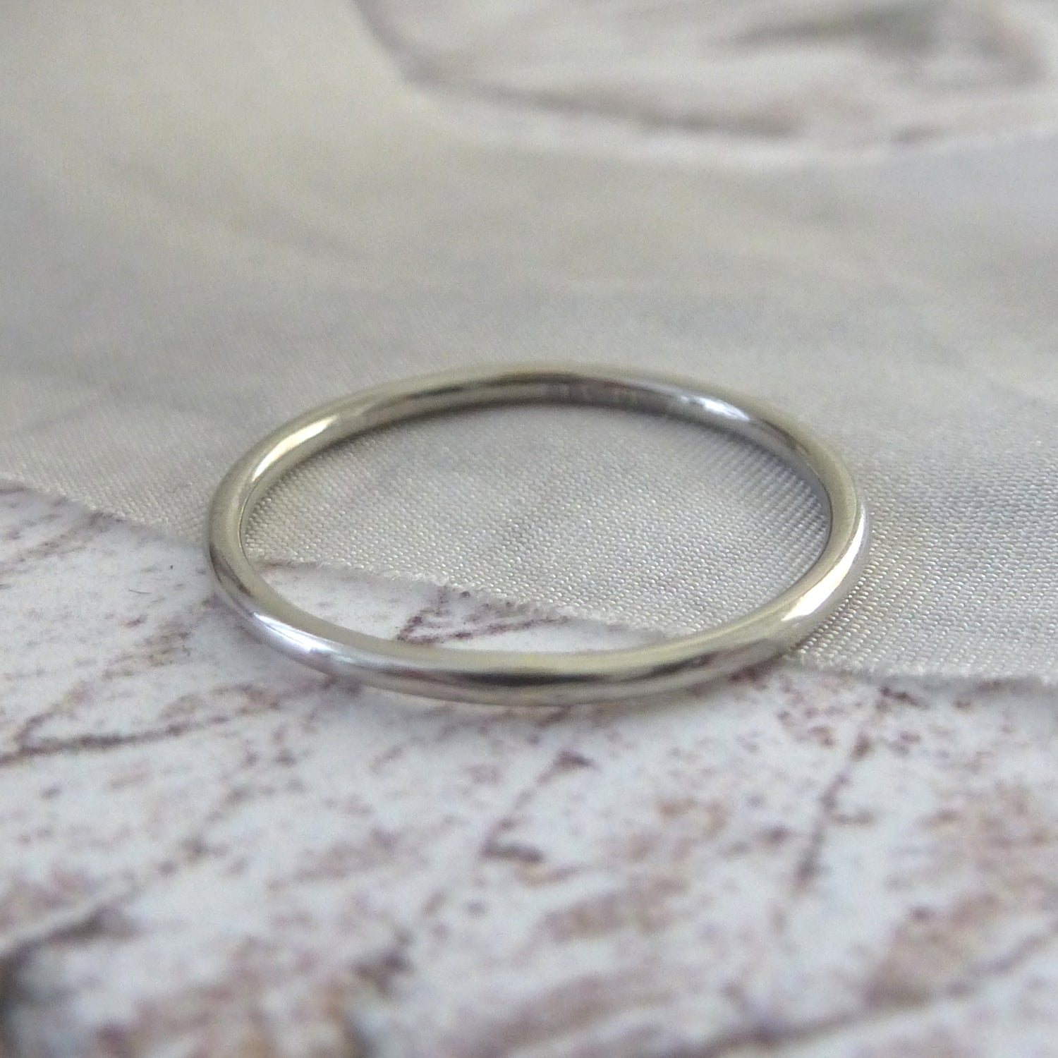 1.2mm round band in 18ct white gold, smooth finish, close up on piece of ribbon