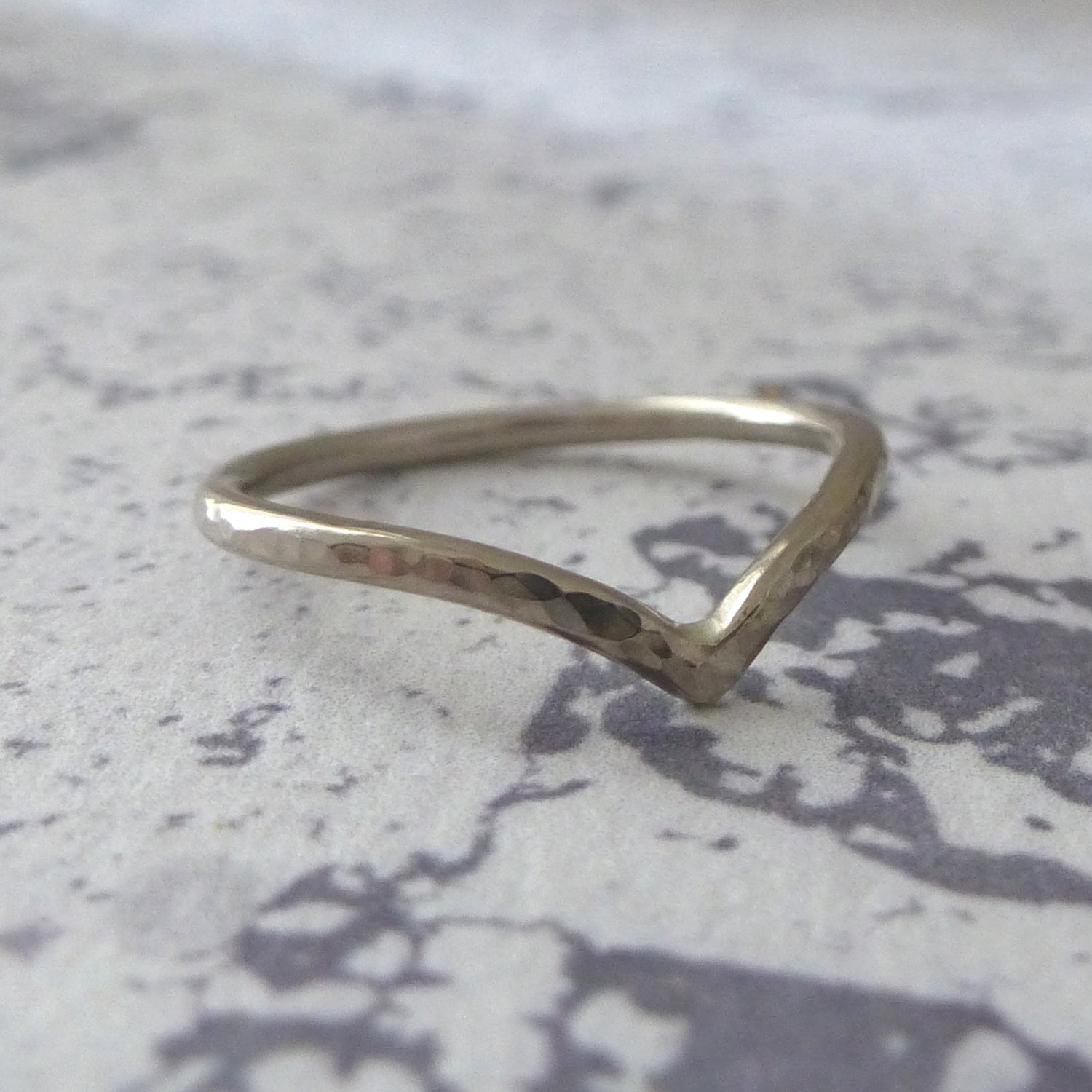 18ct white gold wishbone ring, hammered finish, sitting on marbled paper