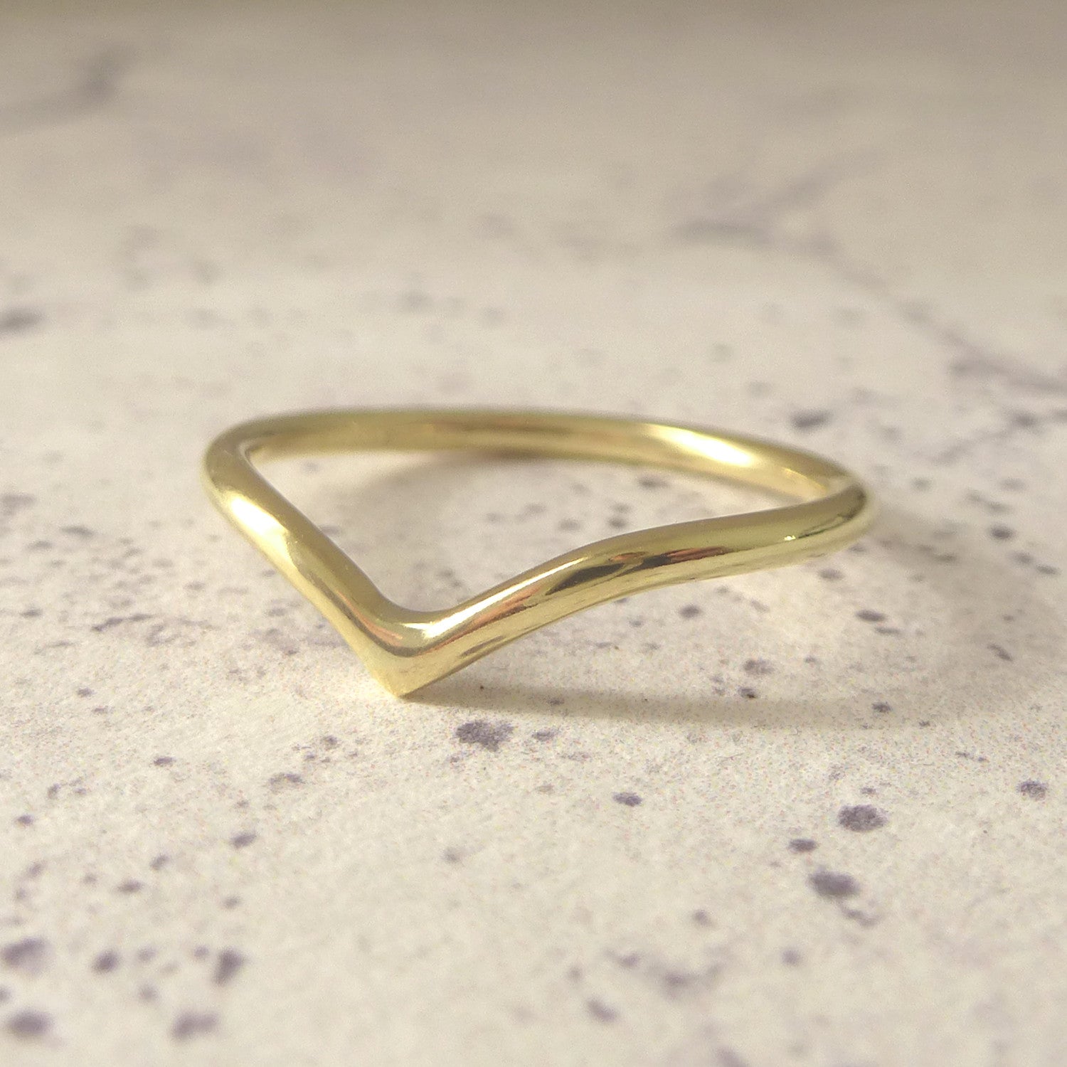 18ct yellow gold wishbone wedding ring sitting on paper background
