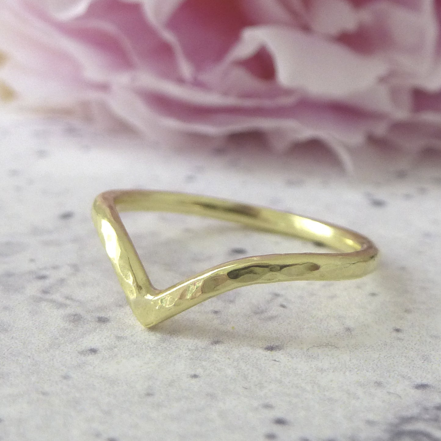 18ct gold hammered wishbone wedding ring, flower in background.