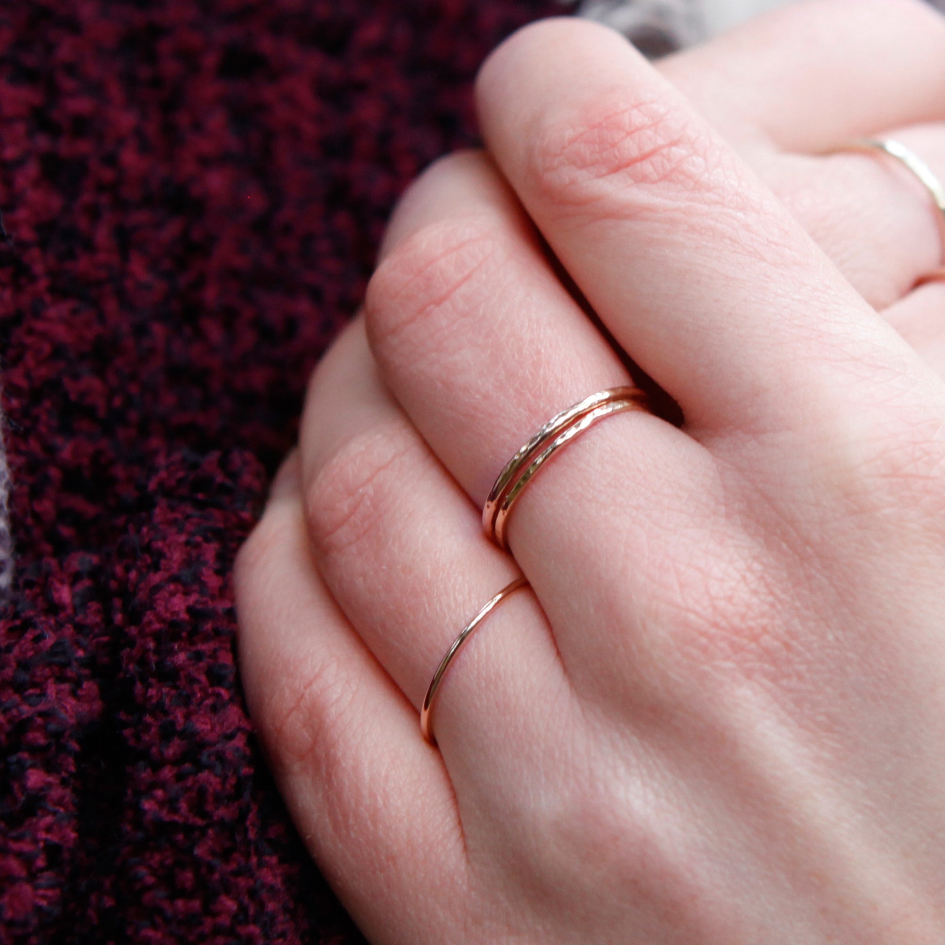 A close up of a hand wearing skinny rings, two 1mm and one 1.2mm, in 9ct gold