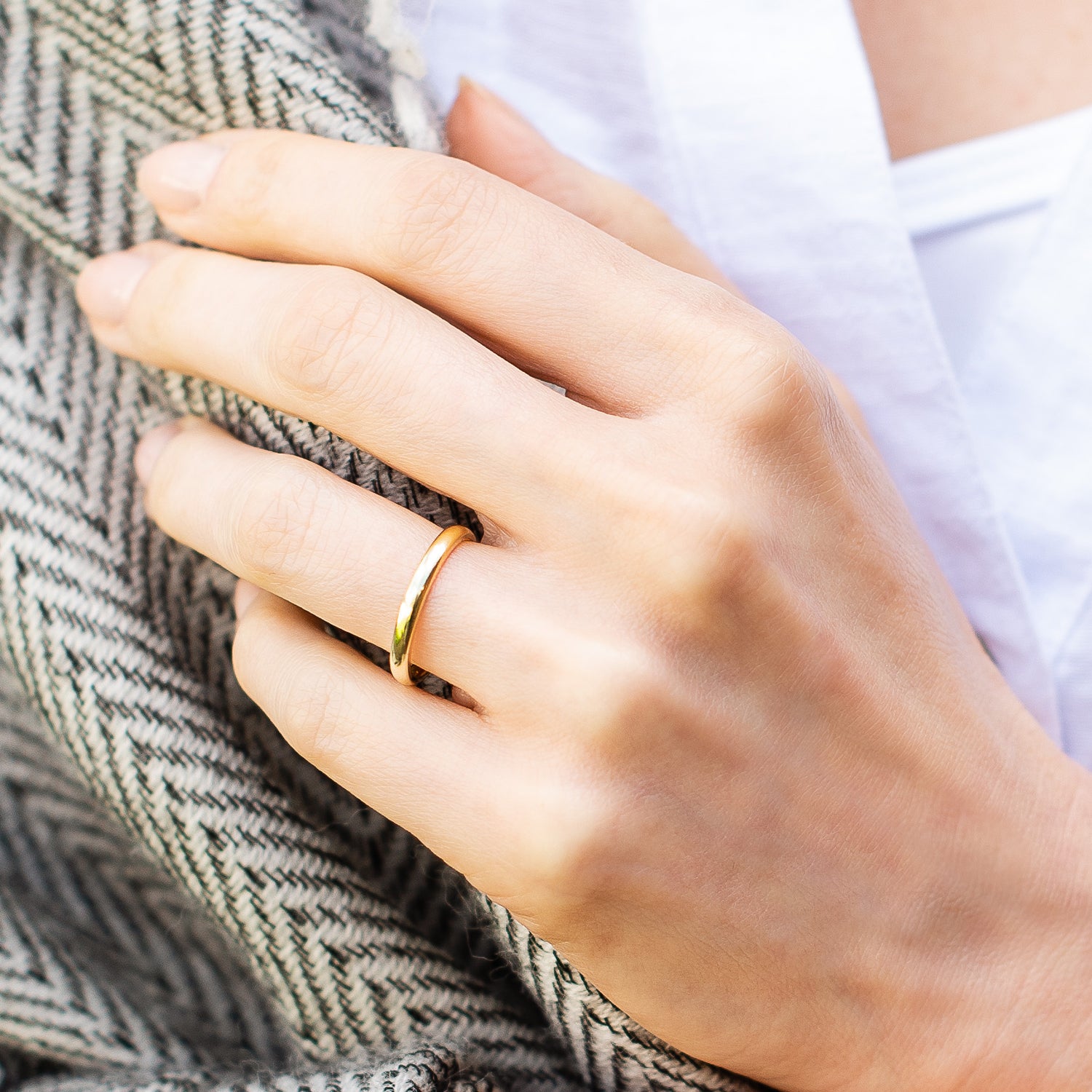2.3mm D shaped rings, 18ct yellow gold, recycled, being worn in front of a black and white scarf