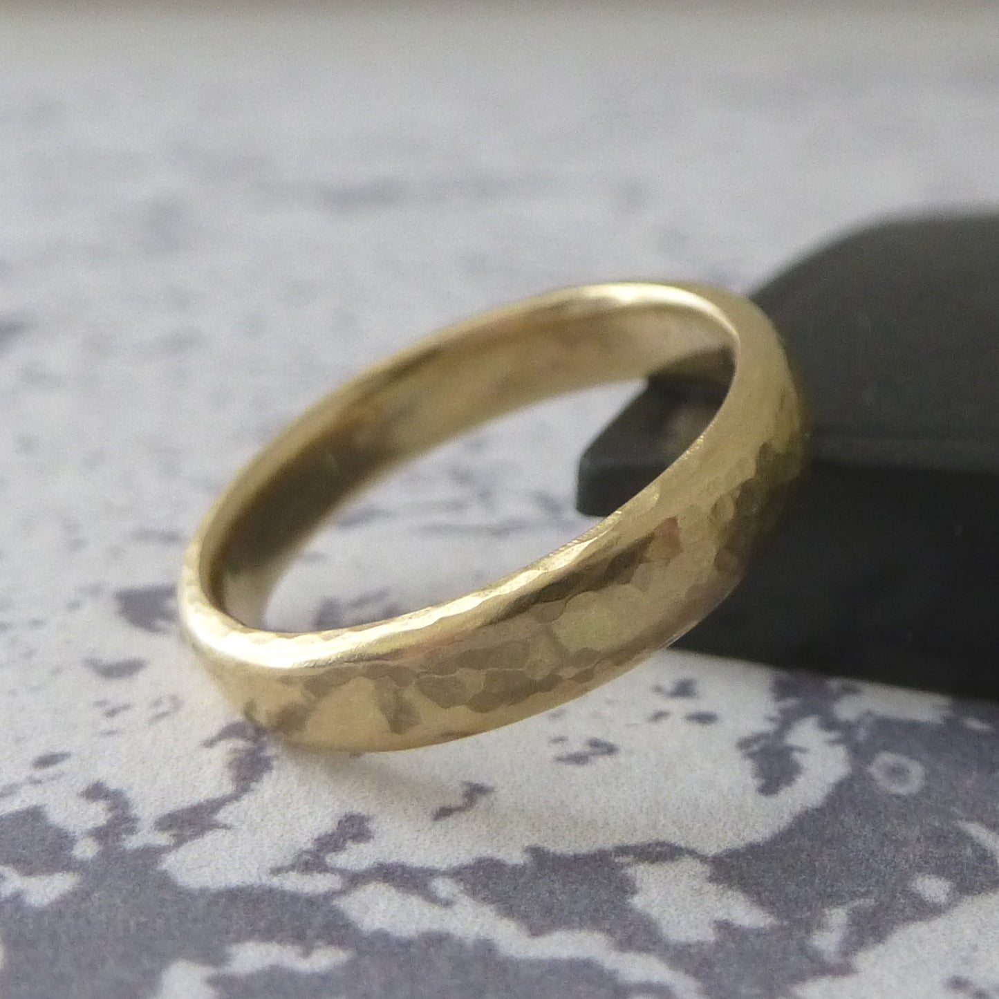 A 3mm wedding band in 18ct yellow gold with hammered finish