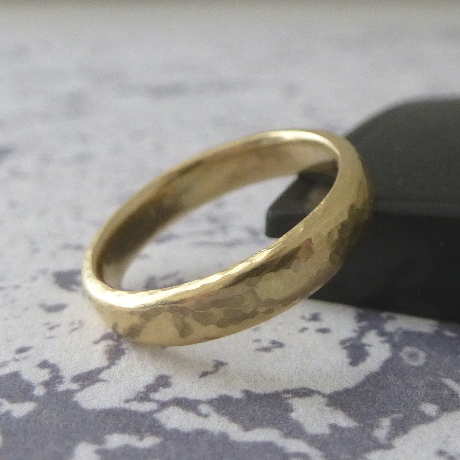 A 3mm wedding band in 18ct yellow gold with hammered finish