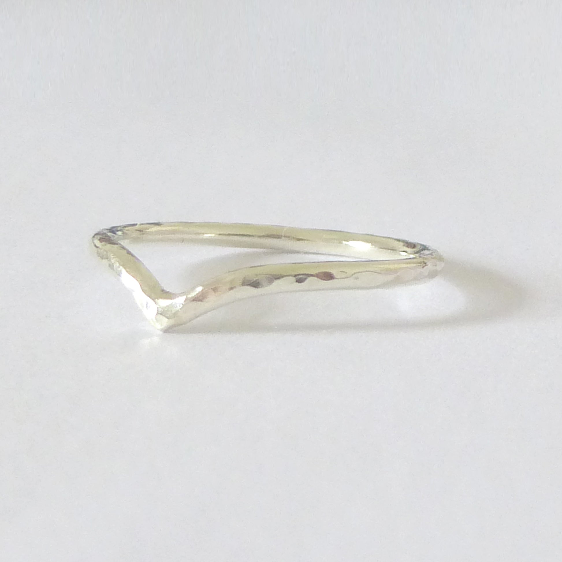 A hand-shaped 9ct gold wishbone ring with a subtle hammer finish on a white background.