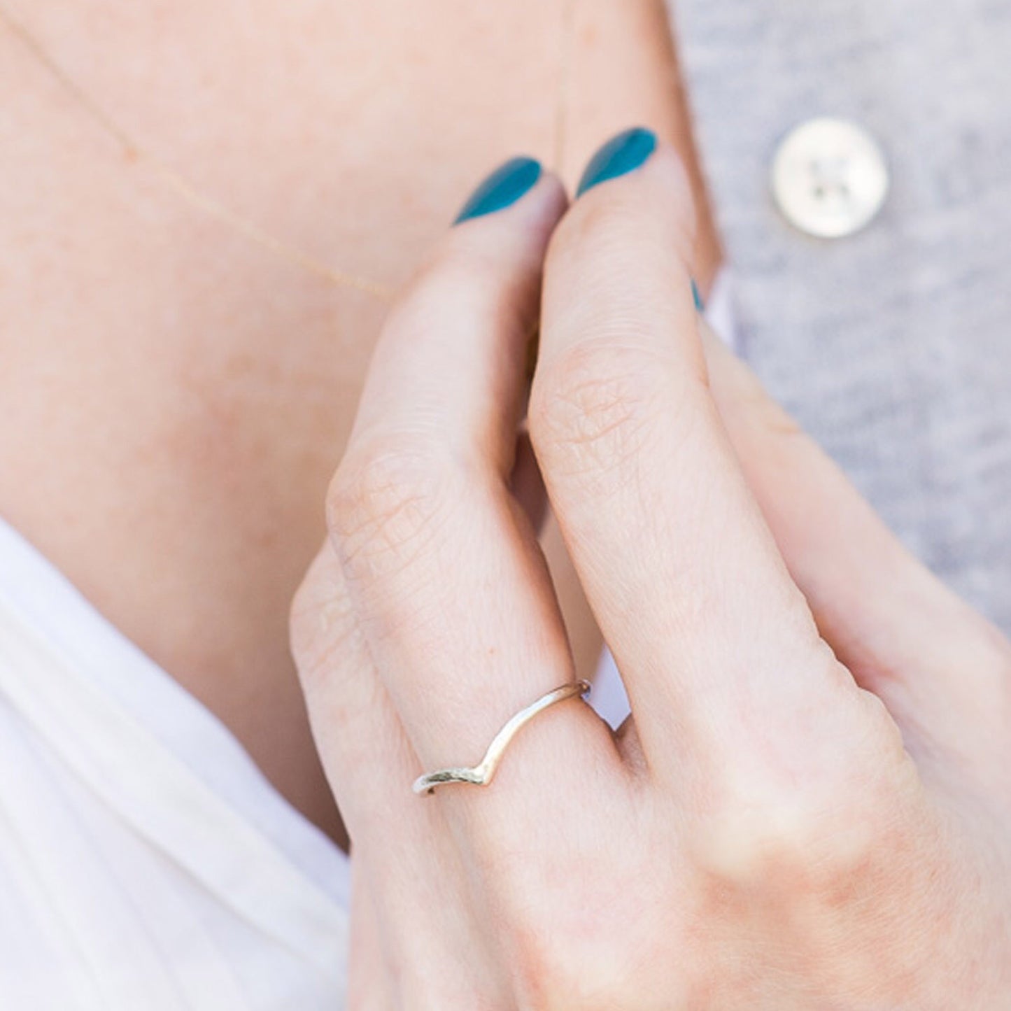 Thin wishbone ring in 9ct white gold with hammered finish, being worn