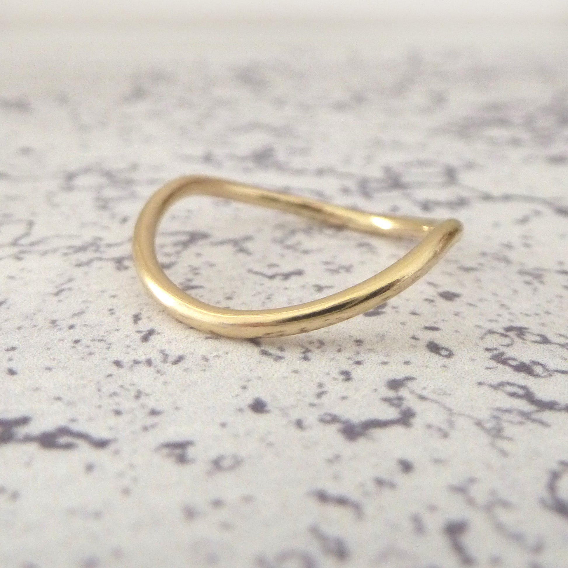A 9ct gold wishbone ring with a 1.5mm diameter, displayed on a textured surface.