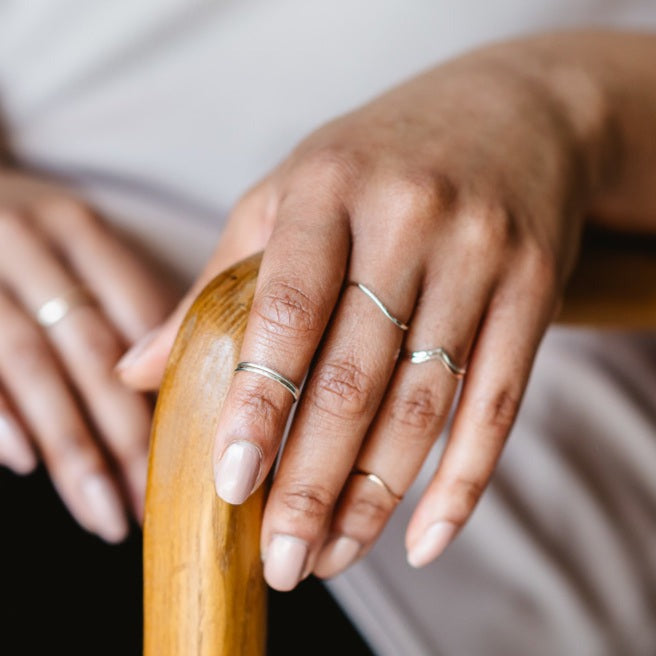 A hand wearing a selection of thin rings in sterling silver and 9ct gold