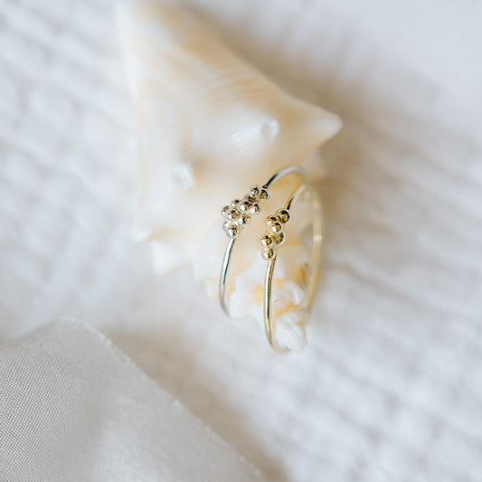 two rings with bubble design top and thin ring bands, one in sterling silver and one in gold. 