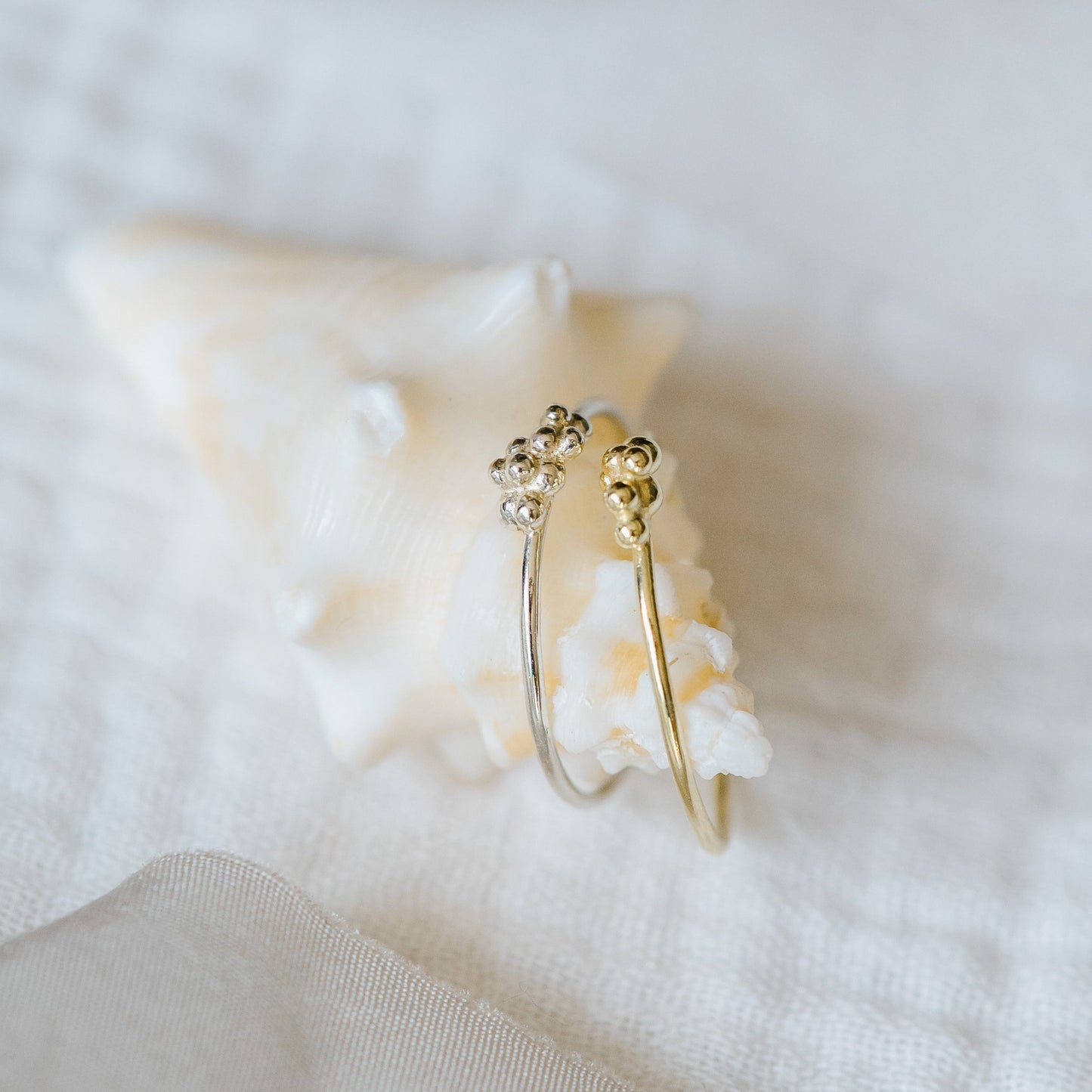 A pair of thin rings with bubbles sitting on a seashell. 