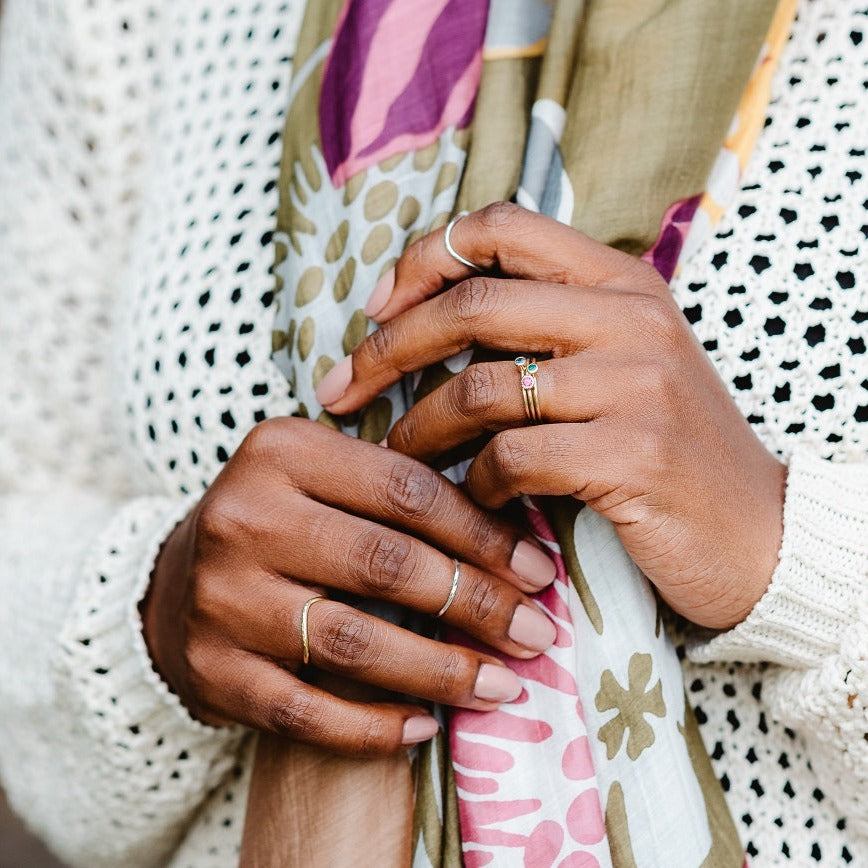Two hands holding a scarf with a selection of rings