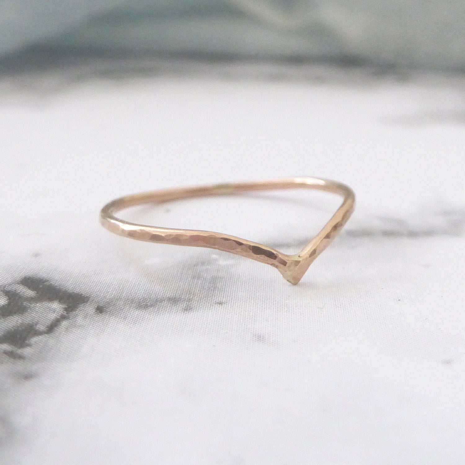 Thin wishbone ring rose gold on marble paper background
