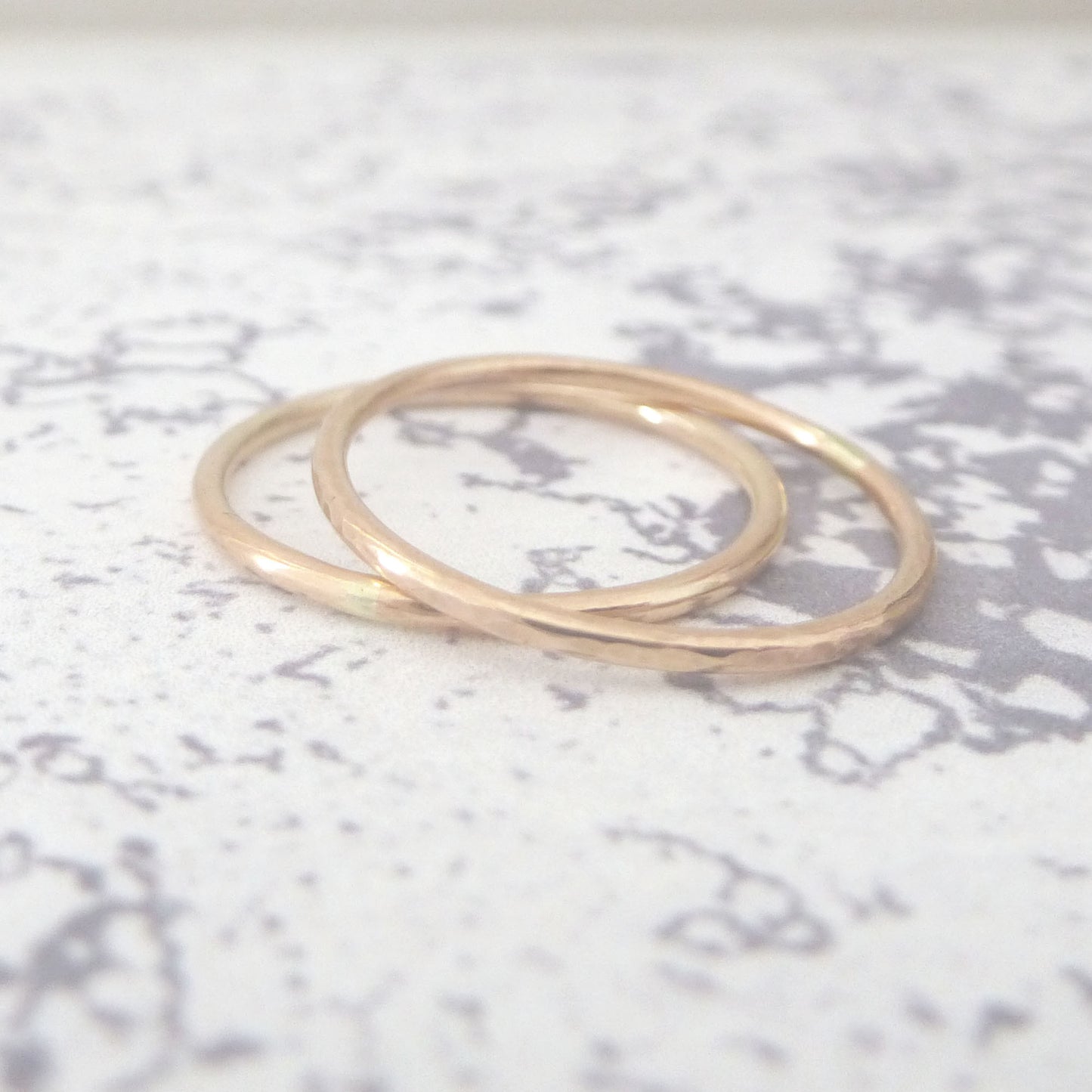 A pair of slim bands in recycled 9ct rose gold, one hammered one smooth