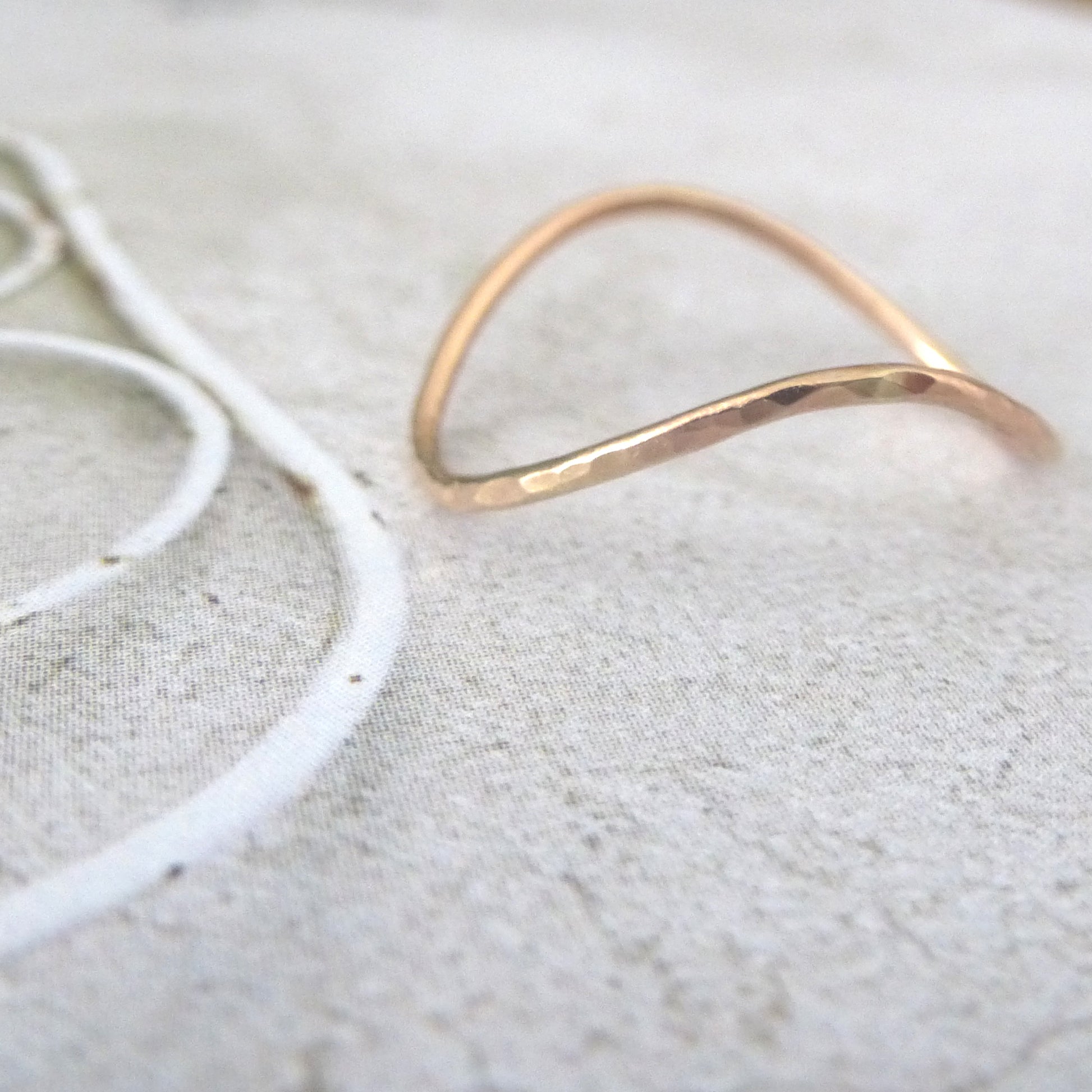 Rose gold wishbone ring sitting on a photo background