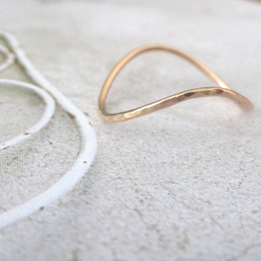 Rose gold wishbone ring sitting on a photo background