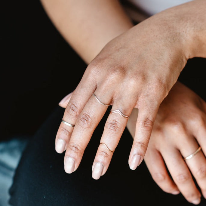 A hand wearing a selection of thin rings in sterling silver and 9ct gold