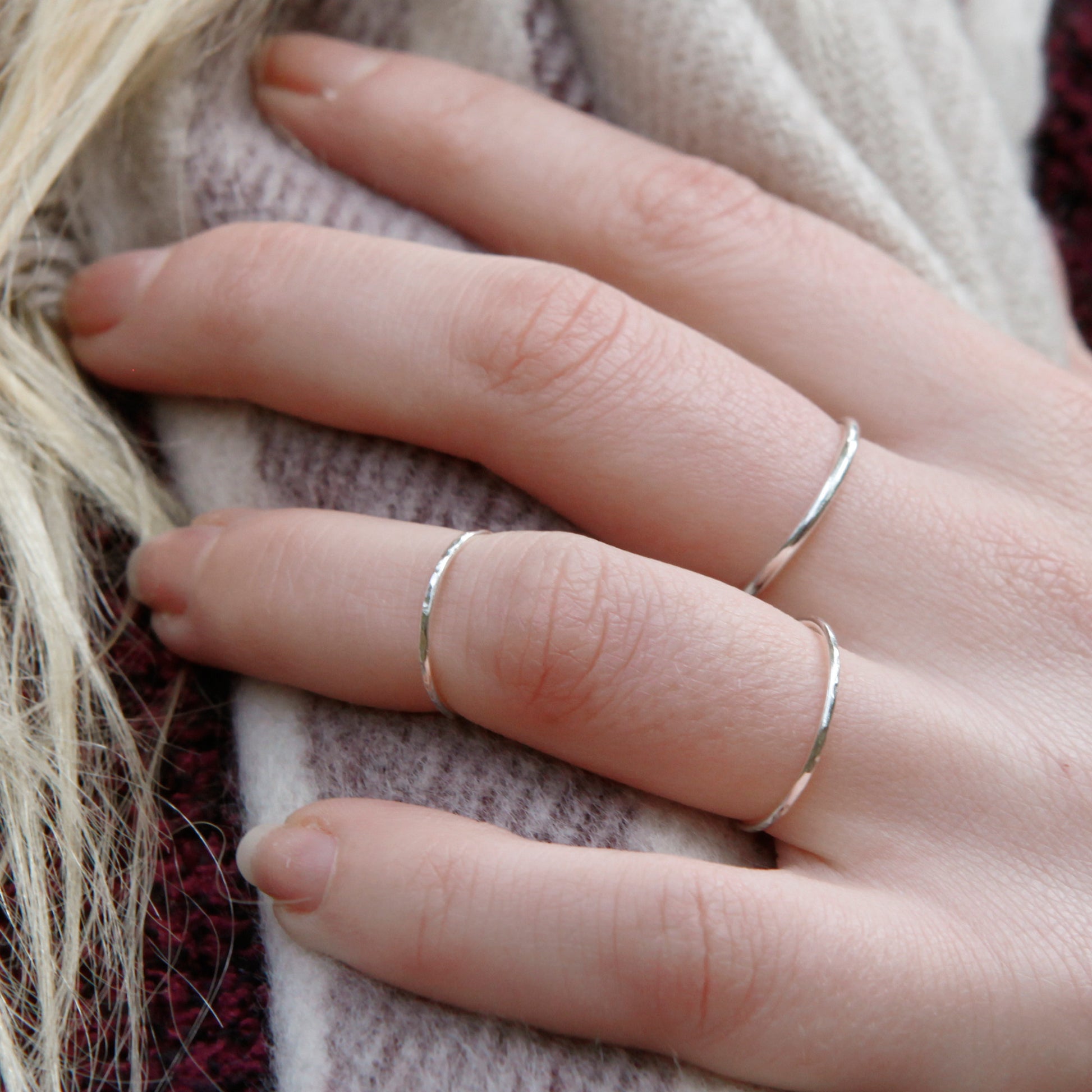 A hand wearing some thin silver rings
