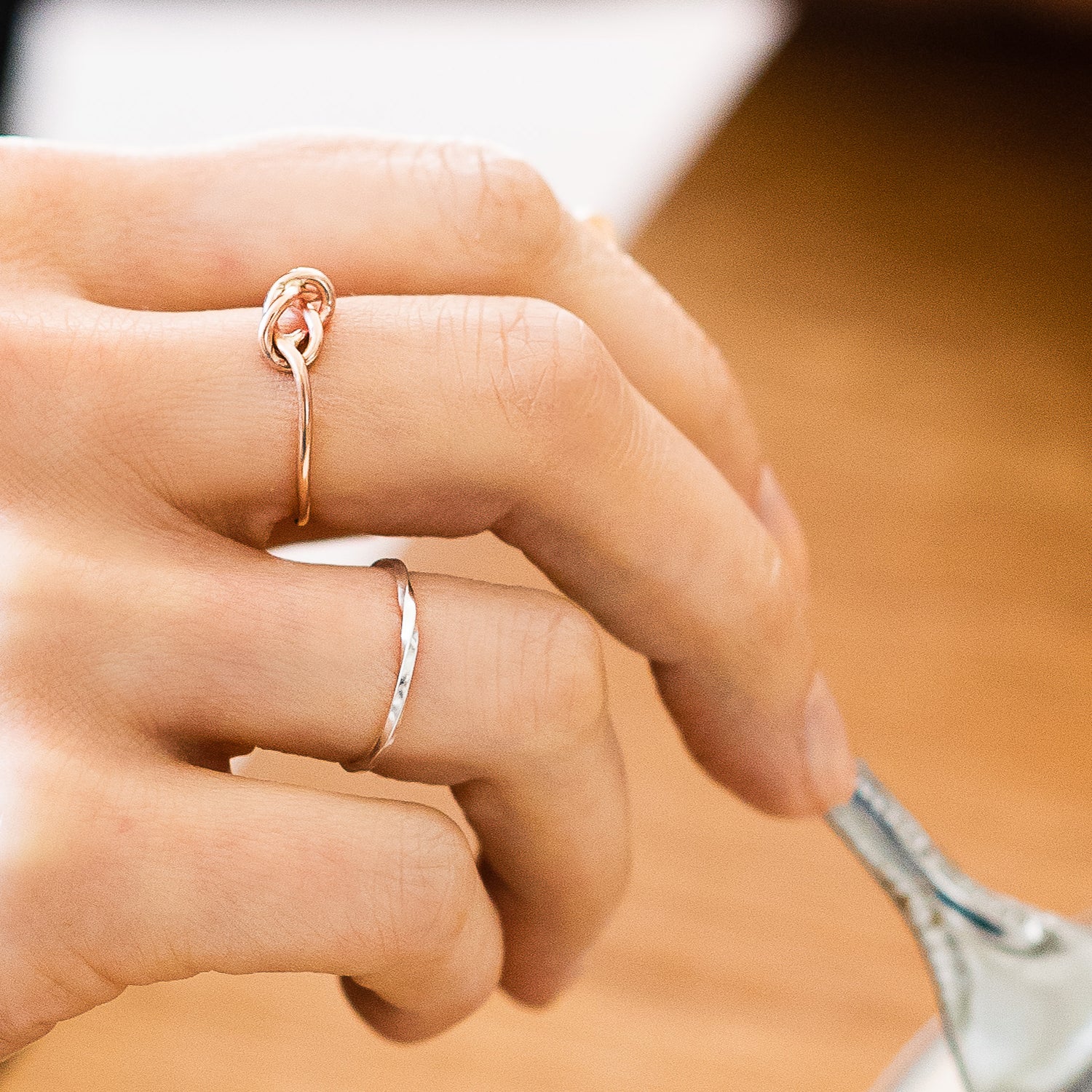 slim rose gold knot ring being worn, hand holding a fork